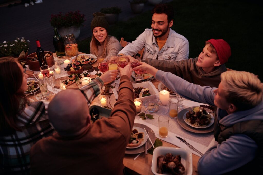 diverse friends toasting at table with candles in garden
